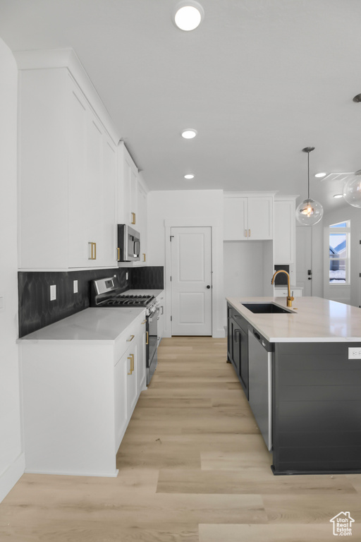 Kitchen with white cabinetry, backsplash, sink, hanging light fixtures, and appliances with stainless steel finishes