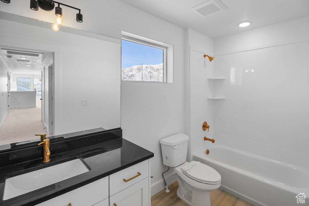 Full bathroom featuring vanity, toilet, wood-type flooring, and shower / bathing tub combination