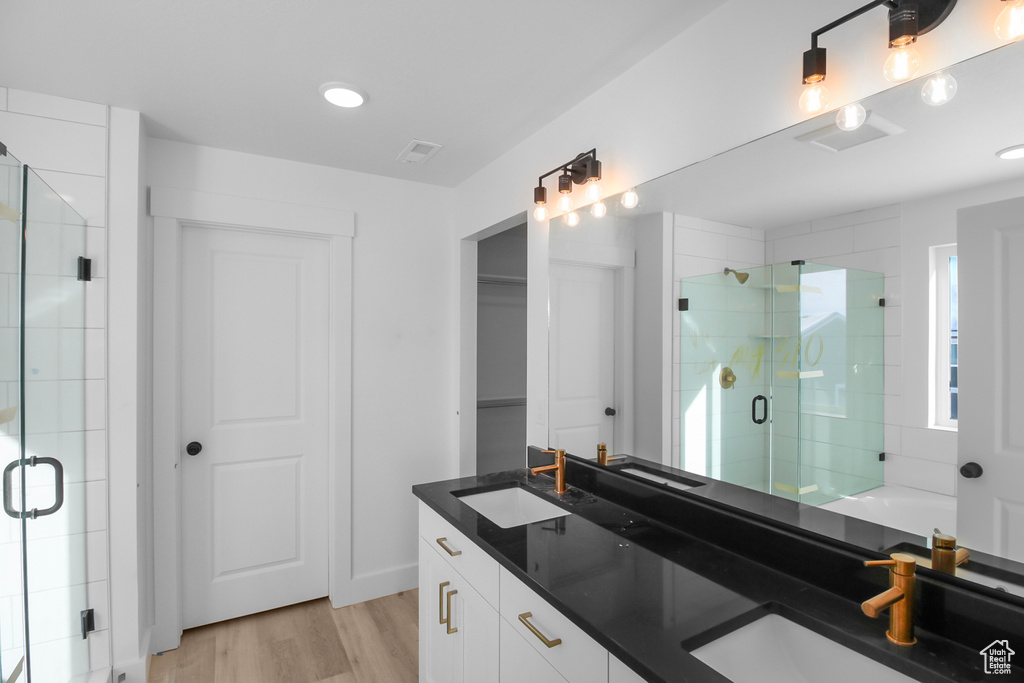 Bathroom with hardwood / wood-style floors, an enclosed shower, and vanity