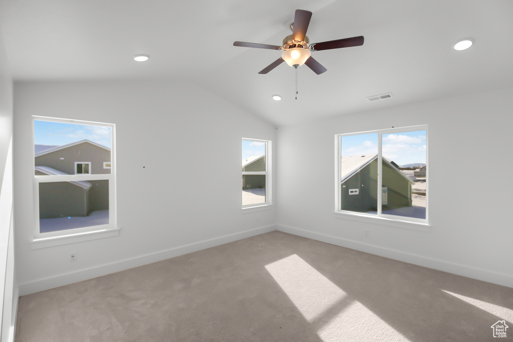 Spare room featuring lofted ceiling, light colored carpet, and ceiling fan