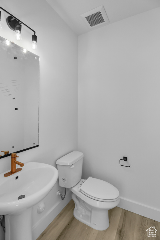 Bathroom featuring toilet, wood-type flooring, and sink