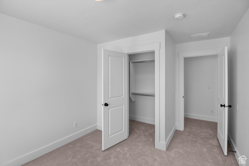 Unfurnished bedroom with a closet and light carpet