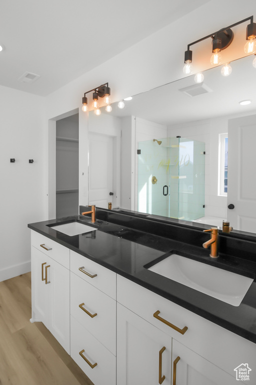 Bathroom with a shower with shower door, hardwood / wood-style floors, and vanity