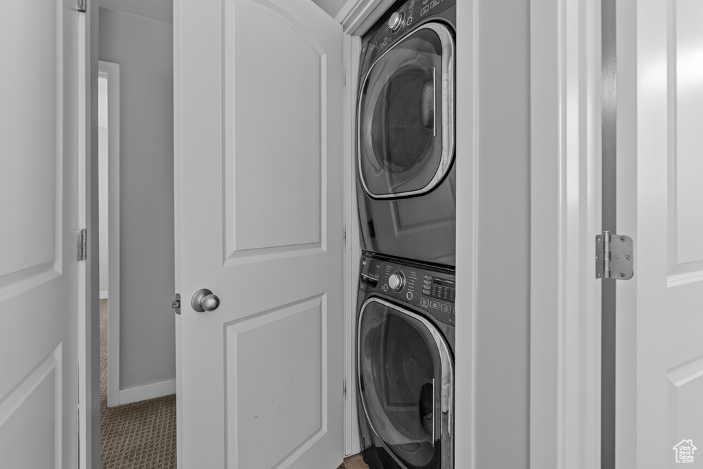 Laundry room with stacked washer and clothes dryer and tile patterned floors