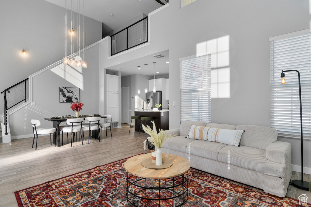 Living room with plenty of natural light, a high ceiling, a notable chandelier, and light wood-type flooring