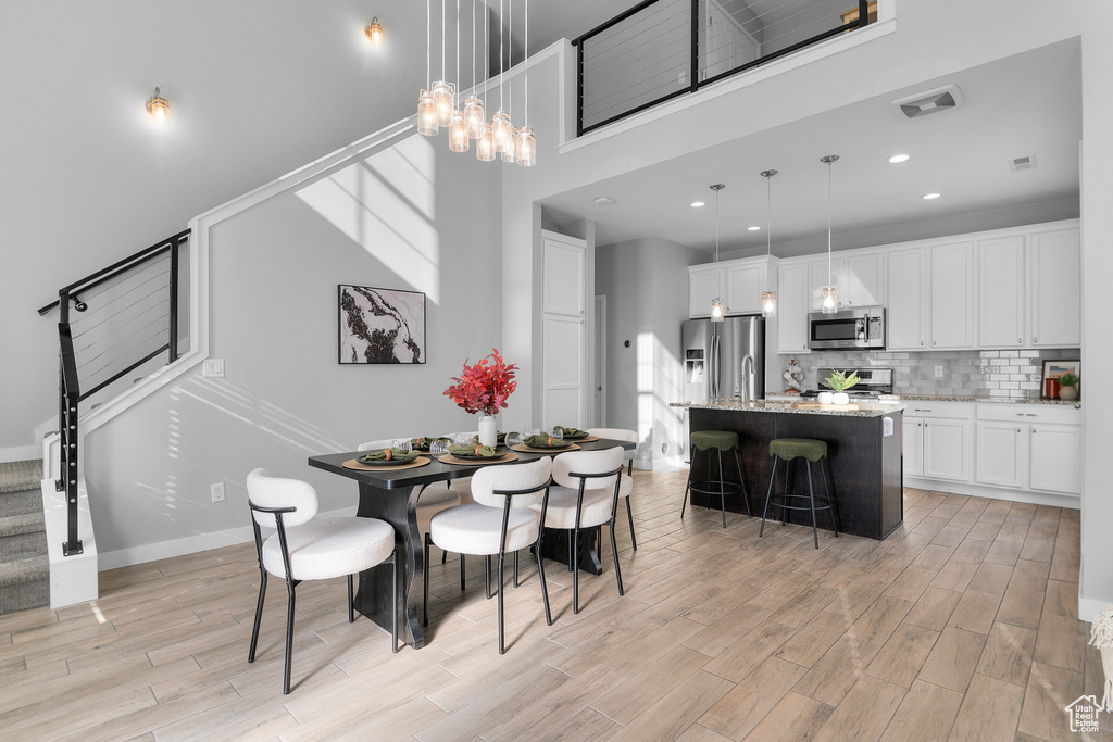 Dining room with a towering ceiling and light hardwood / wood-style floors