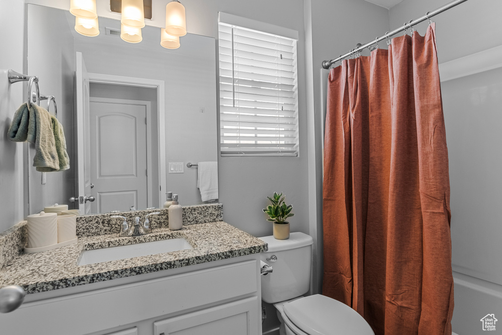 Bathroom with vanity, toilet, and a shower with shower curtain