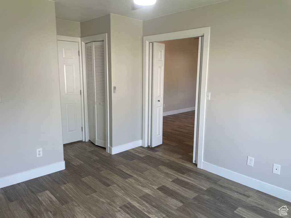 Unfurnished bedroom with dark wood-type flooring and a closet