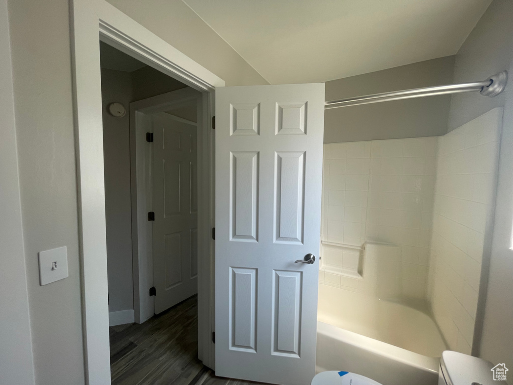 Bathroom featuring toilet, hardwood / wood-style floors, and shower / washtub combination