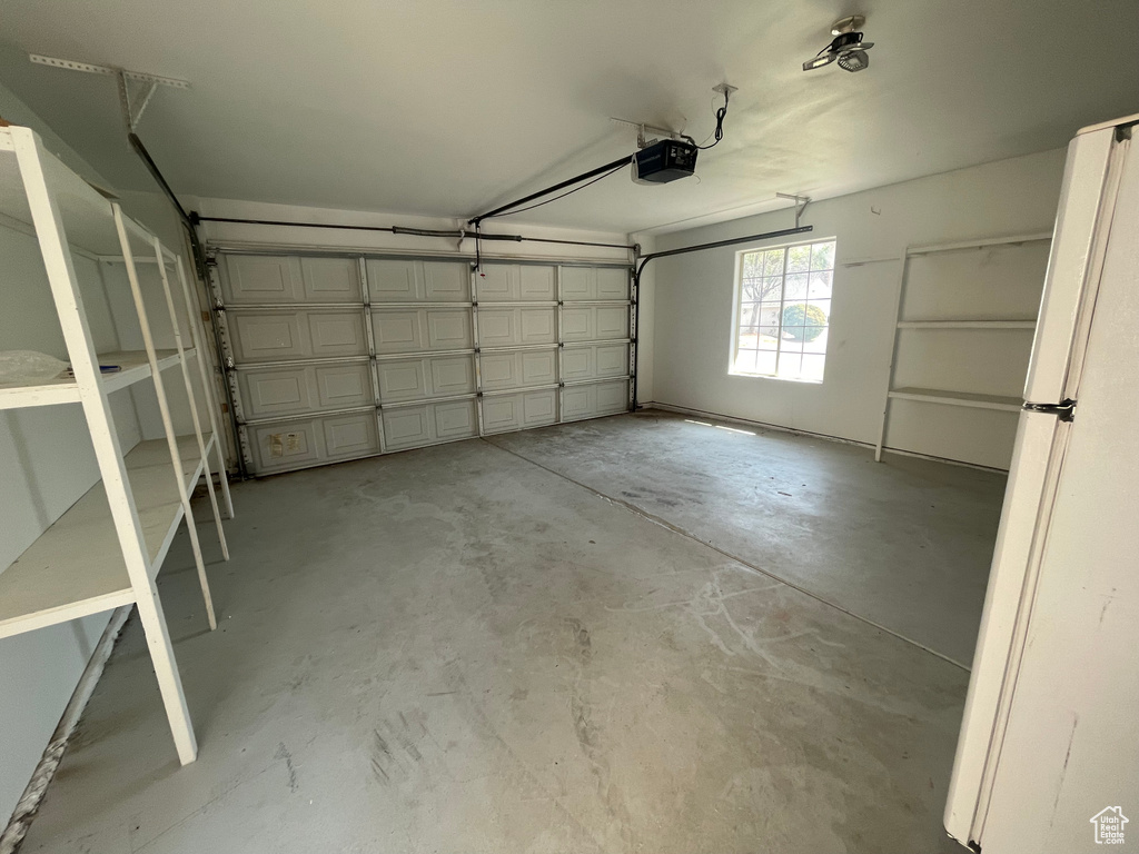 Garage featuring white fridge and a garage door opener