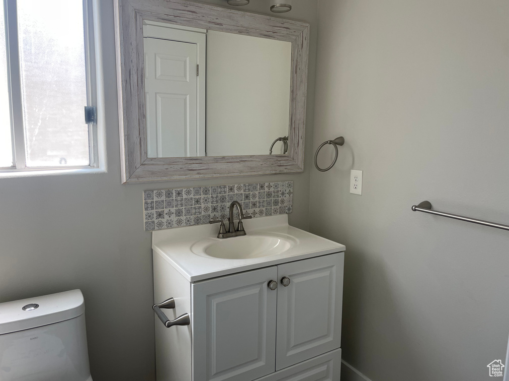 Bathroom with toilet, decorative backsplash, and vanity