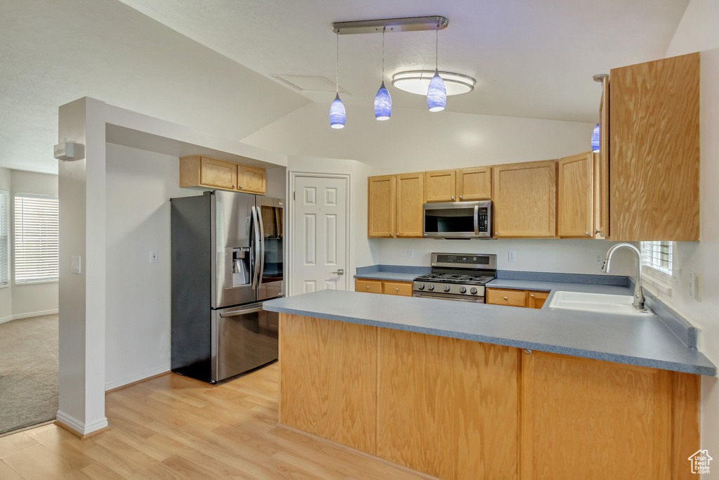 Kitchen with light hardwood / wood-style flooring, appliances with stainless steel finishes, sink, kitchen peninsula, and pendant lighting