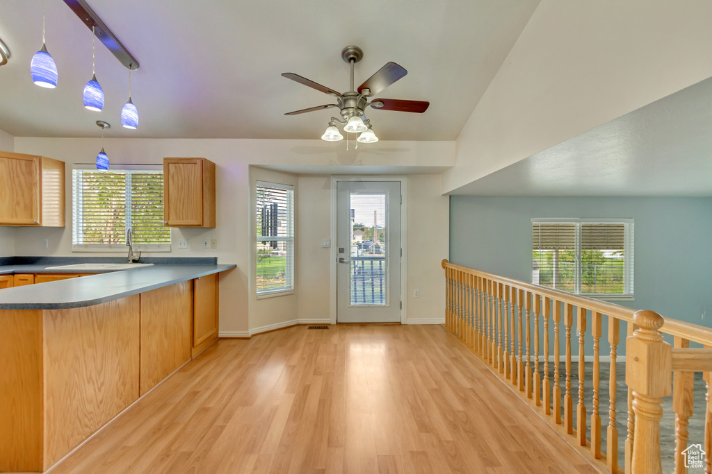 Kitchen with light brown cabinetry, hanging light fixtures, light wood-type flooring, lofted ceiling, and ceiling fan