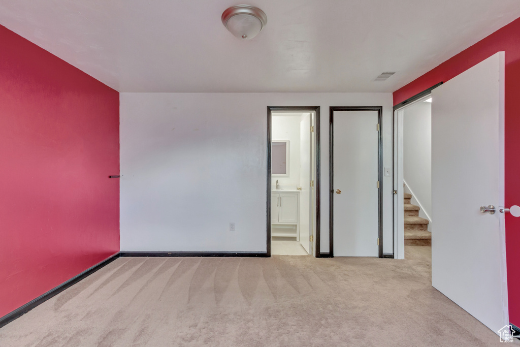 Unfurnished bedroom with light colored carpet and ensuite bathroom