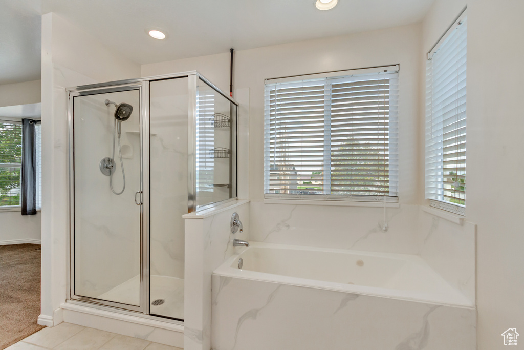 Bathroom featuring tile patterned flooring, a wealth of natural light, and shower with separate bathtub