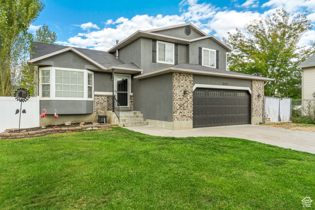 View of front facade featuring a front yard and a garage