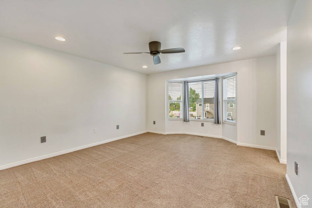 Empty room with light colored carpet and ceiling fan