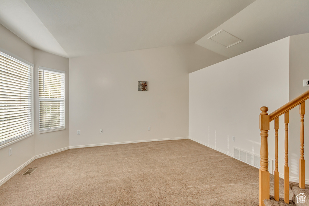 Carpeted spare room with vaulted ceiling