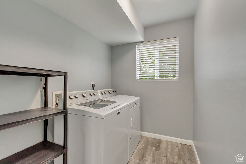 Laundry area with independent washer and dryer and light hardwood / wood-style floors