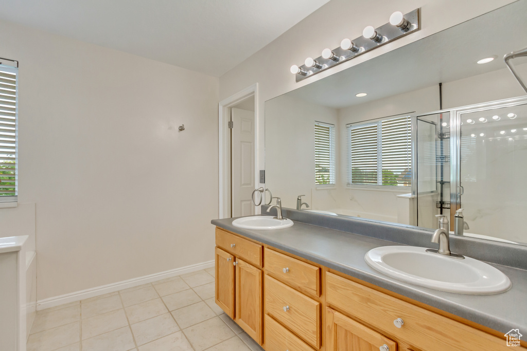 Bathroom featuring vanity, a wealth of natural light, walk in shower, and tile patterned flooring