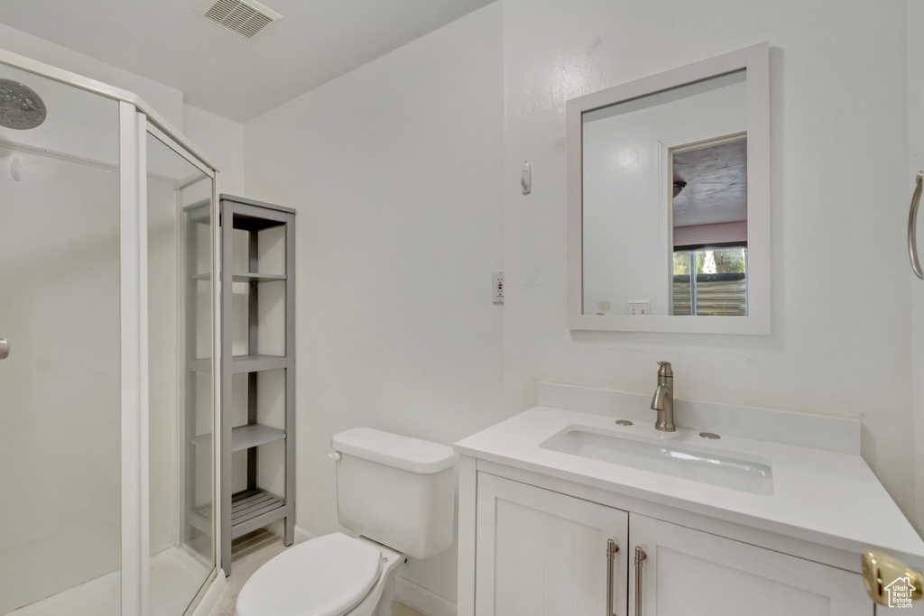 Bathroom with toilet, a shower with door, and vanity