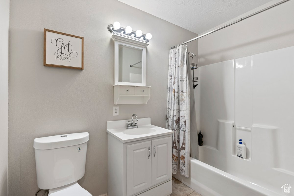 Full bathroom featuring toilet, tile patterned floors, vanity, a textured ceiling, and shower / tub combo