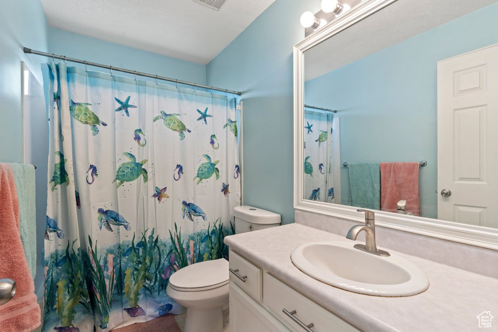 Bathroom with a shower with curtain, toilet, and vanity