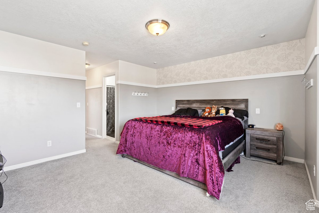 Bedroom featuring a textured ceiling and light carpet