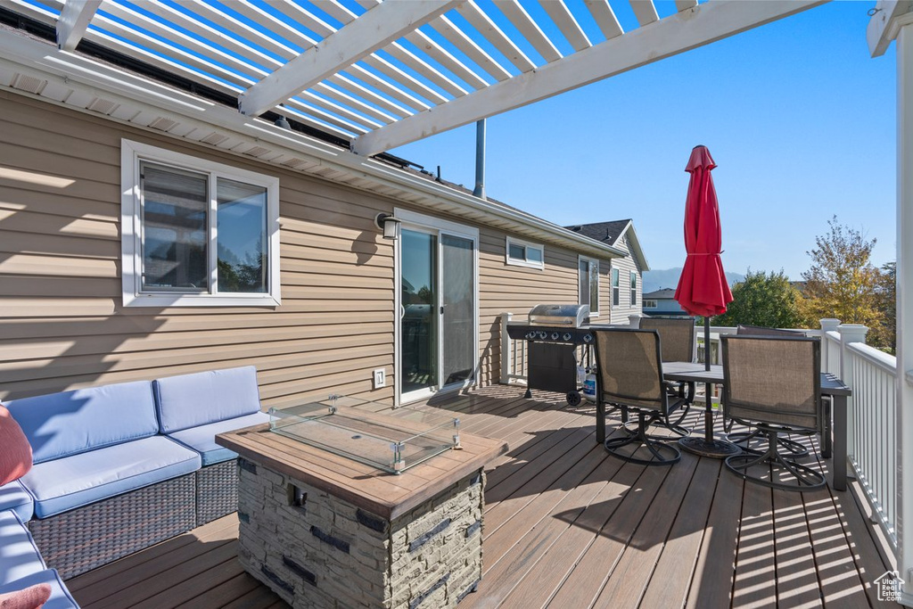 Wooden deck with an outdoor living space with a fire pit and a grill