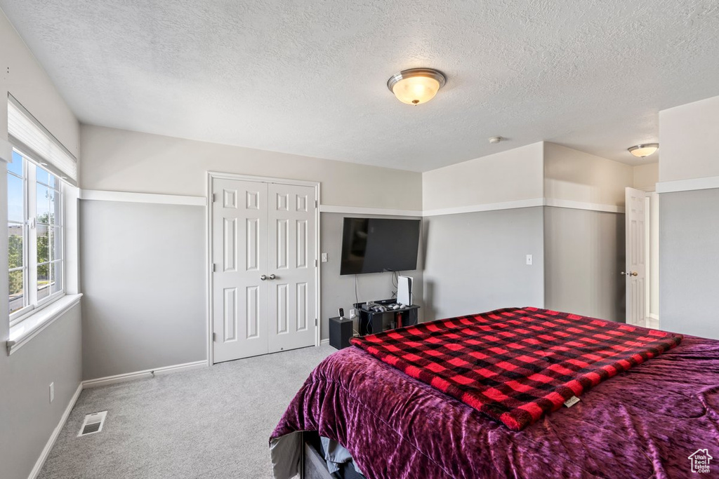 Bedroom featuring a textured ceiling and light colored carpet