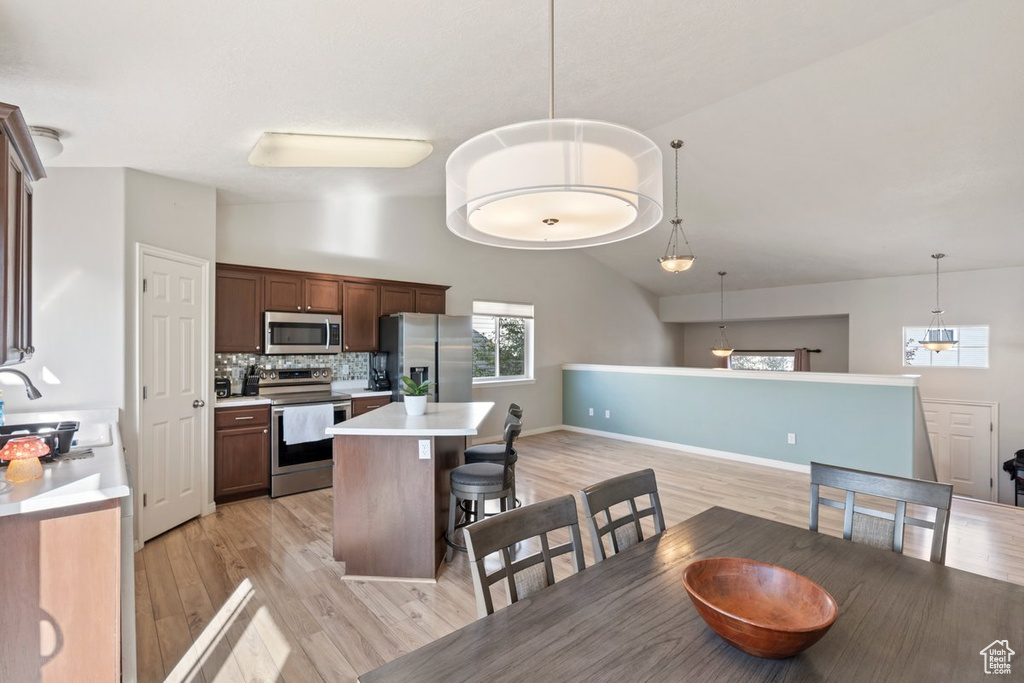 Dining area featuring high vaulted ceiling and light hardwood / wood-style floors