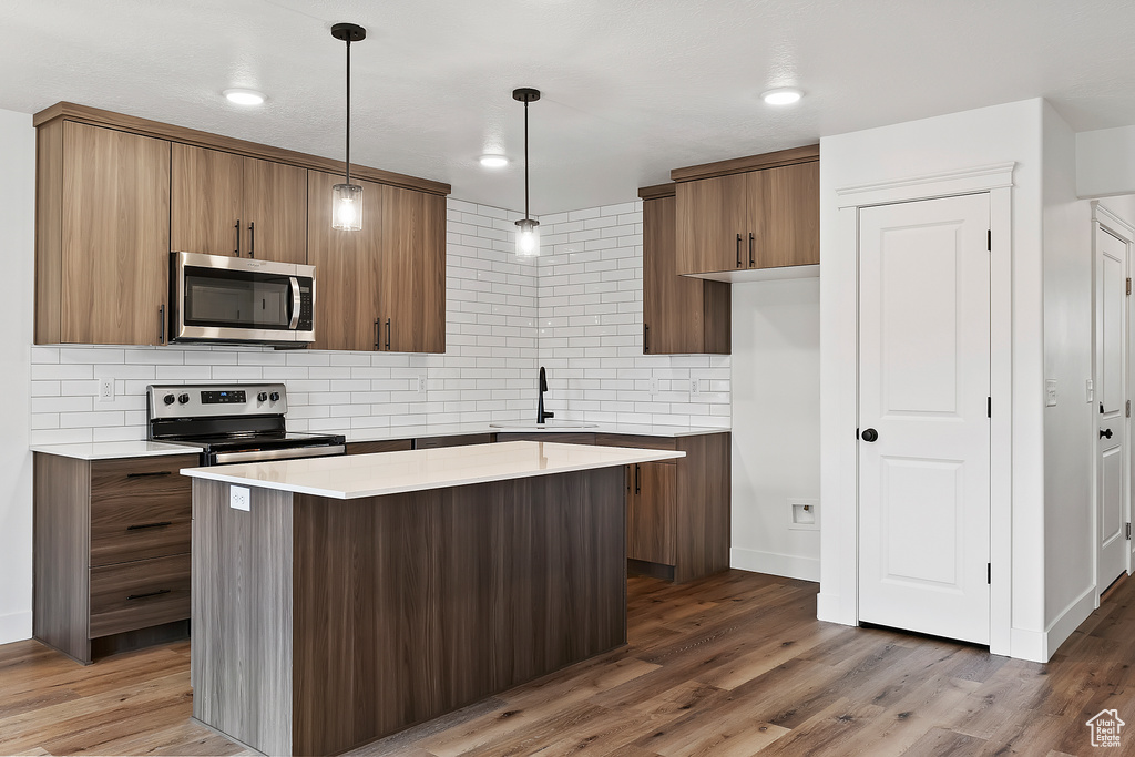 Kitchen featuring a center island, pendant lighting, stainless steel appliances, and dark hardwood / wood-style floors