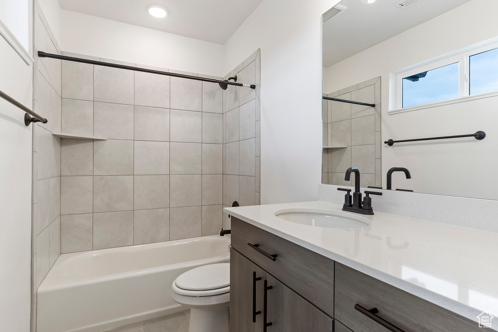 Full bathroom with tiled shower / bath combo, vanity, toilet, and tile patterned flooring