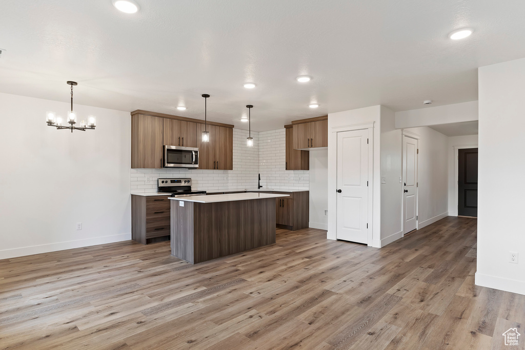 Kitchen featuring appliances with stainless steel finishes, hanging light fixtures, light hardwood / wood-style floors, and a chandelier