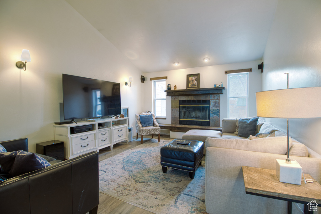 Living room featuring lofted ceiling, light hardwood / wood-style flooring, and a tile fireplace