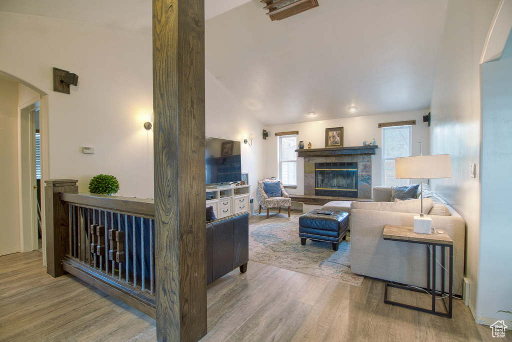 Living room with lofted ceiling, hardwood / wood-style floors, and a fireplace