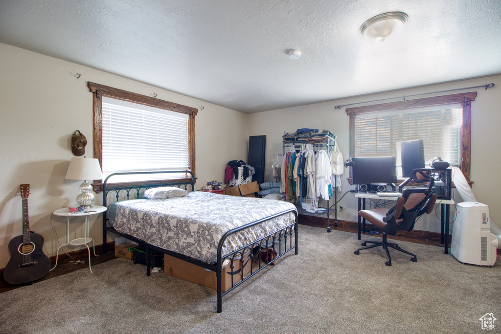 Bedroom with a textured ceiling and light colored carpet