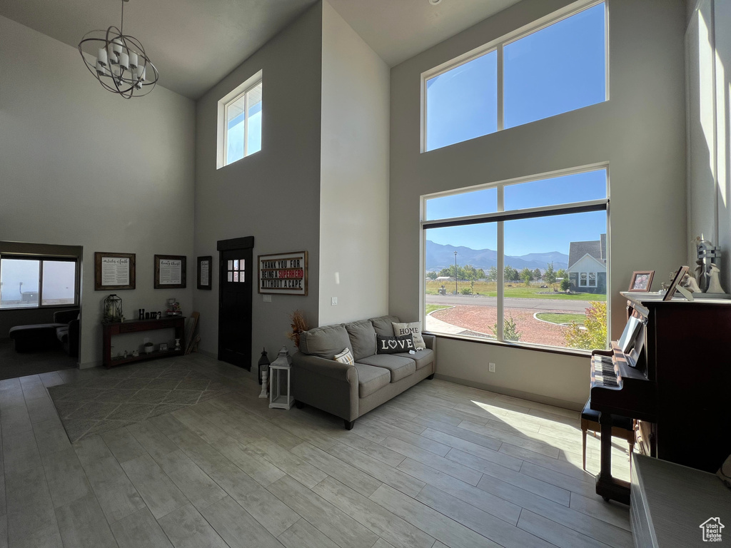 Living room featuring a mountain view, a towering ceiling, light wood-type flooring, and a notable chandelier