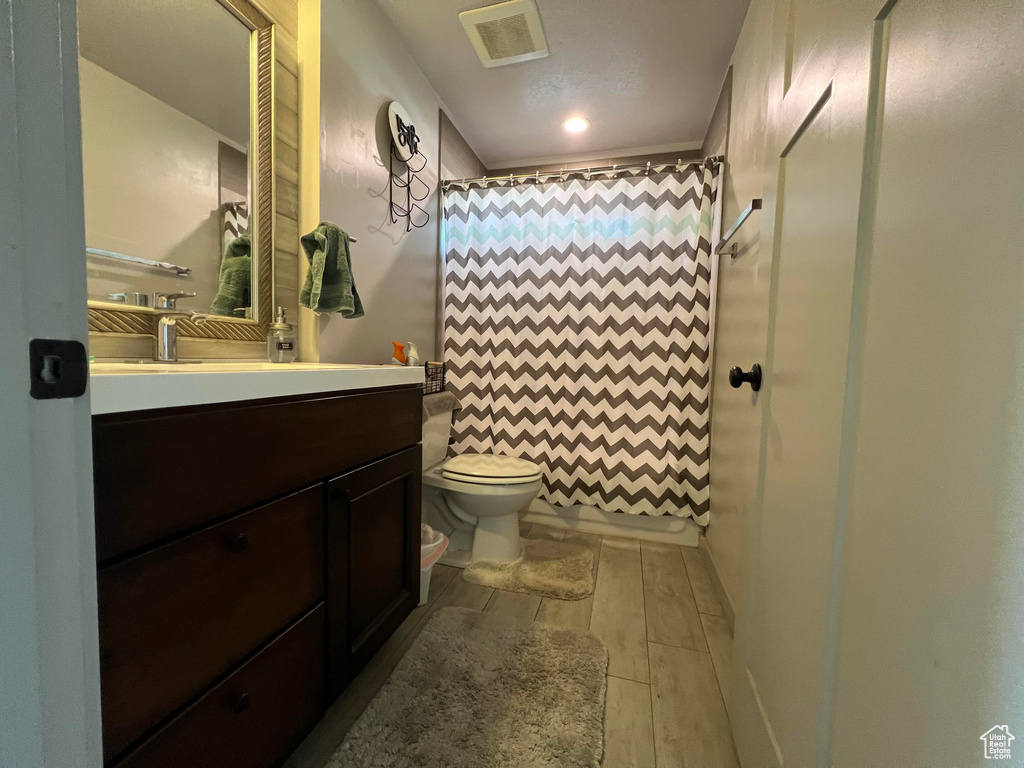 Bathroom featuring hardwood / wood-style flooring, walk in shower, toilet, vanity, and a textured ceiling