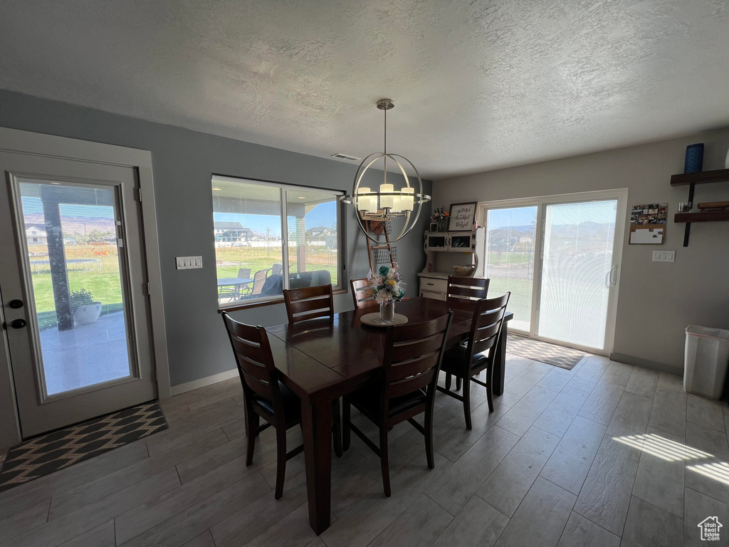 Dining area featuring a textured ceiling, a notable chandelier, and wood-type flooring