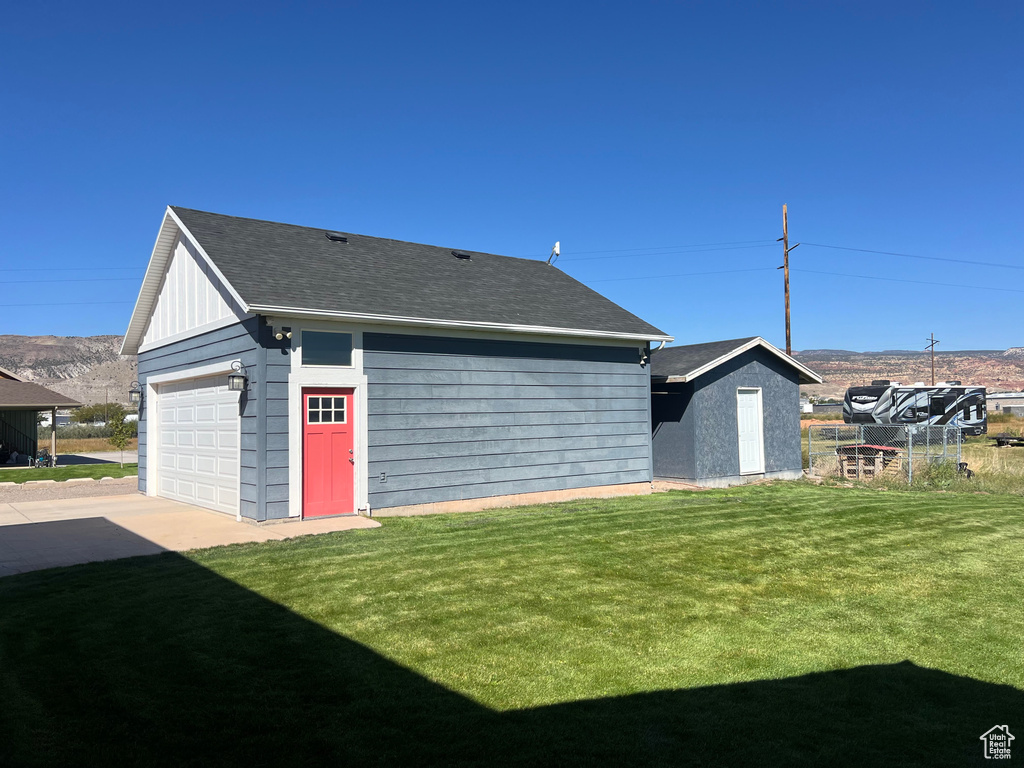 Exterior space featuring a yard, a garage, a mountain view, and a storage shed