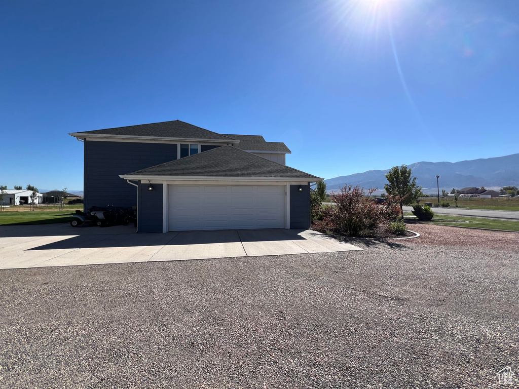 View of side of home with a mountain view and a garage