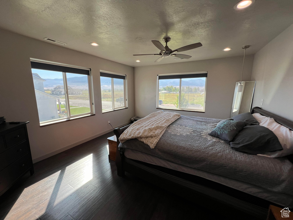 Bedroom with dark wood-type flooring, a textured ceiling, and ceiling fan