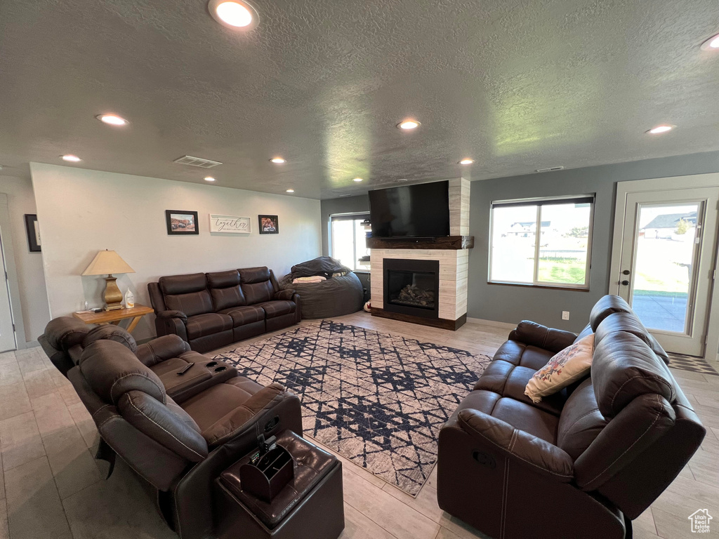 Living room featuring a textured ceiling, a healthy amount of sunlight, and a fireplace