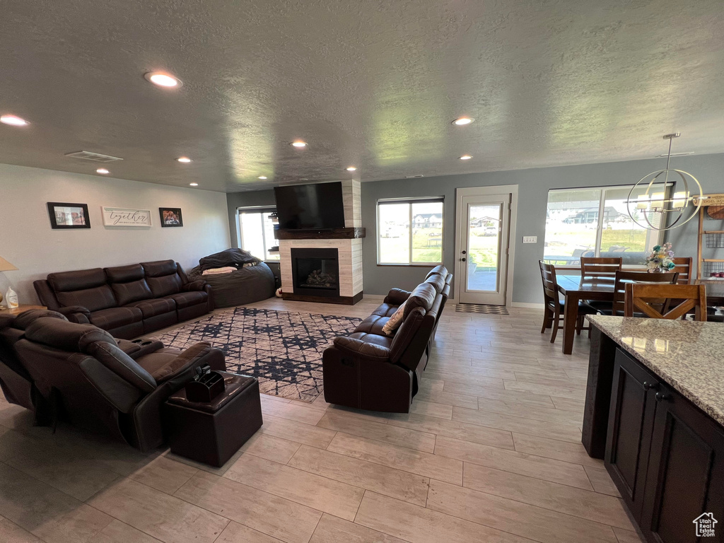 Living room featuring a textured ceiling, a healthy amount of sunlight, light wood-type flooring, and a fireplace