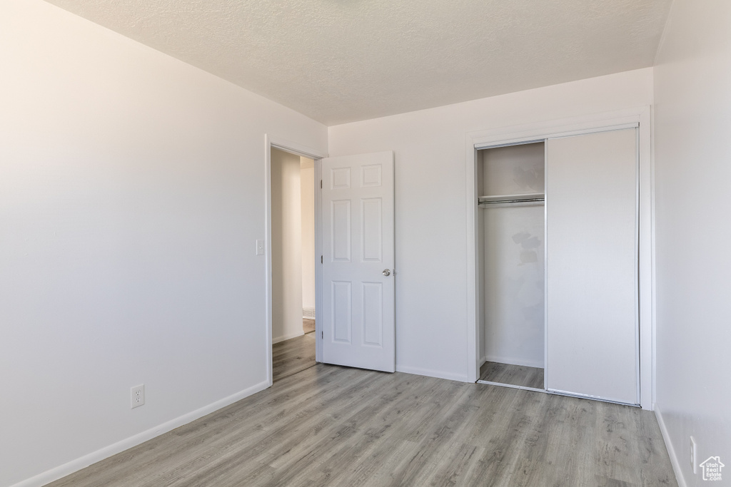 Unfurnished bedroom featuring a textured ceiling, light hardwood / wood-style flooring, and a closet