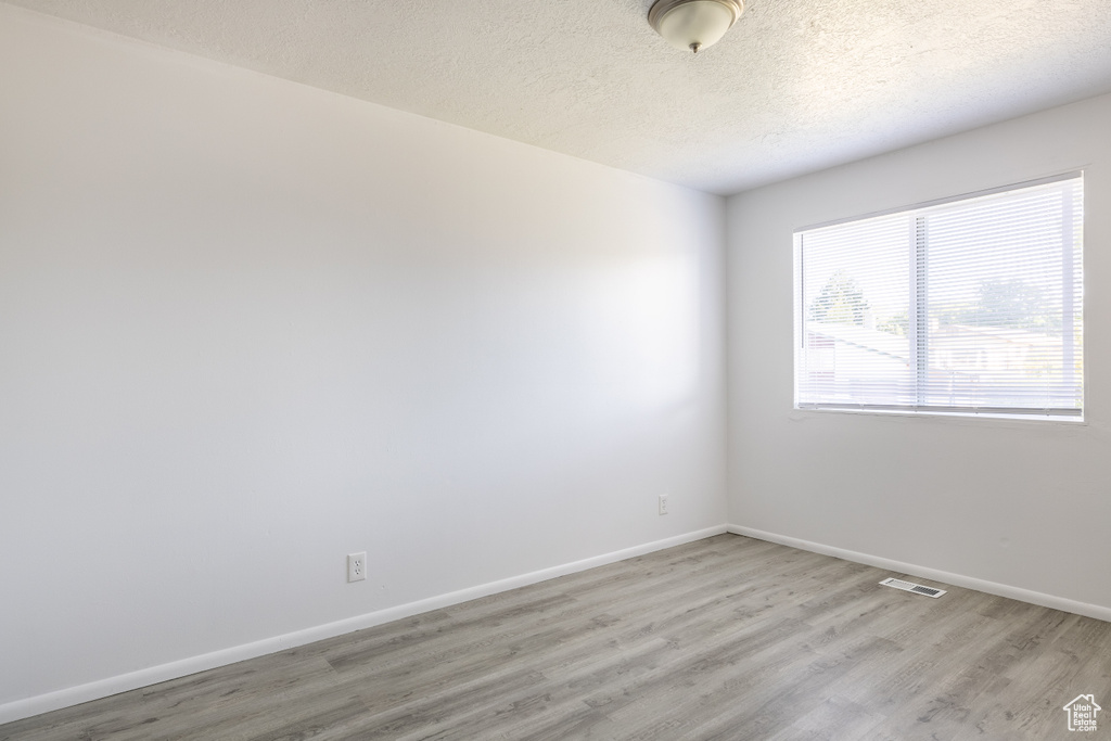 Unfurnished room with hardwood / wood-style flooring and a textured ceiling