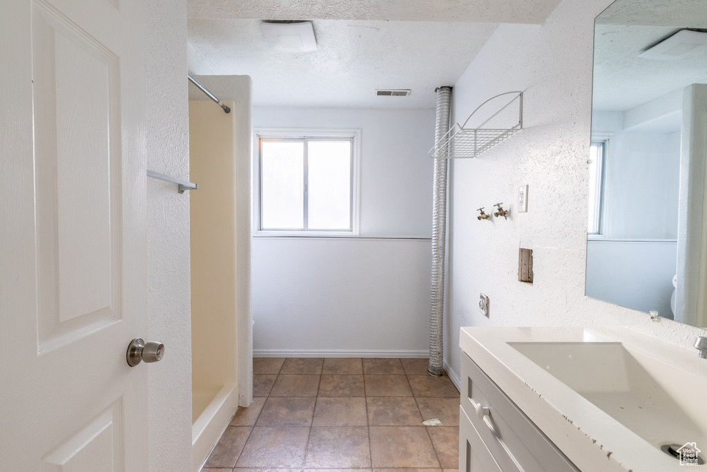 Bathroom with a textured ceiling, vanity, a shower, and tile patterned floors