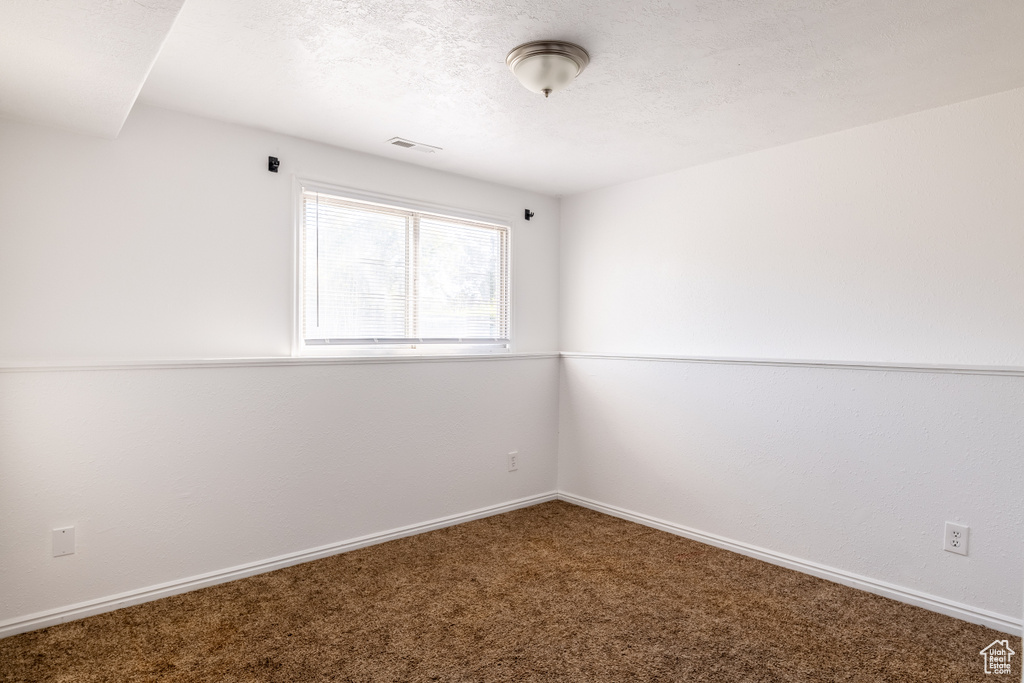 Empty room featuring a textured ceiling and carpet flooring