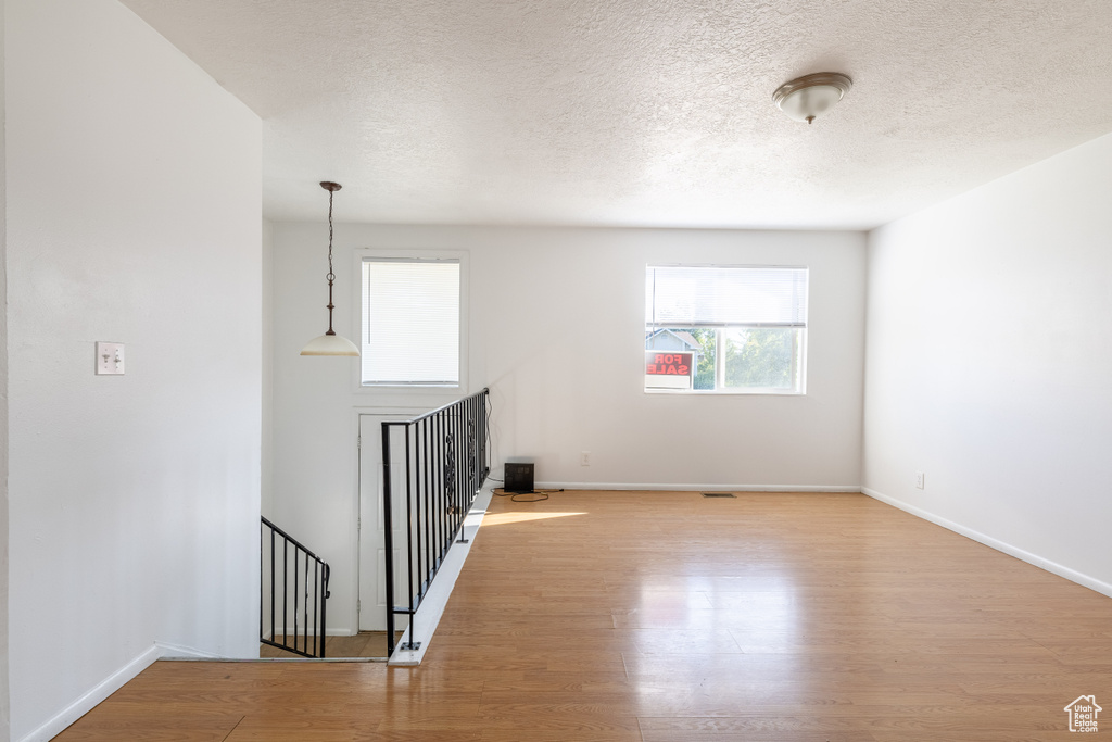 Spare room featuring a textured ceiling and light hardwood / wood-style flooring